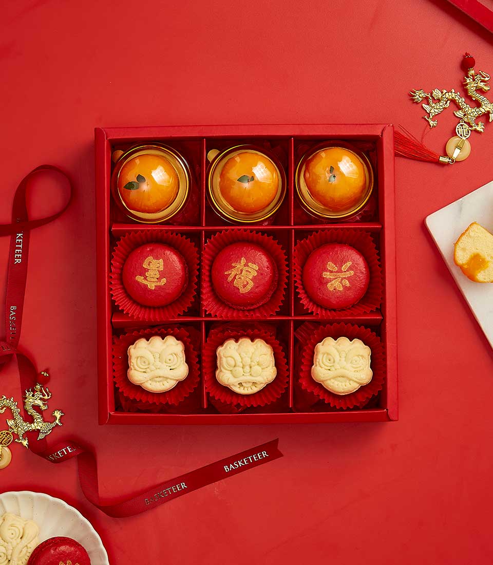 Chinese New Year Sweet Gift In Creamy Mandarin Center Cake, Mandarin Macarons, Mandarin Dragon Cookies In The Red Box With a Bow.