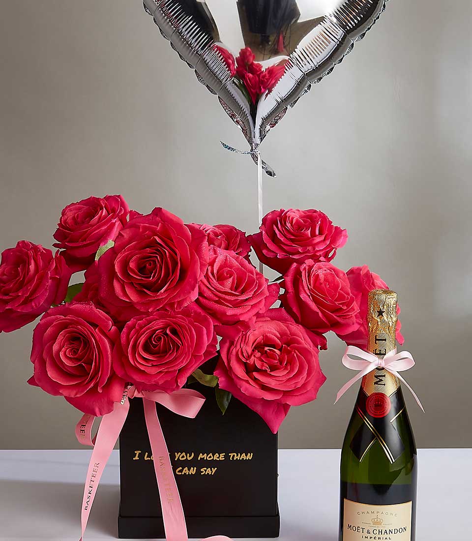 A bouquet of vibrant pink roses in a black vase with a ribbon captioned 