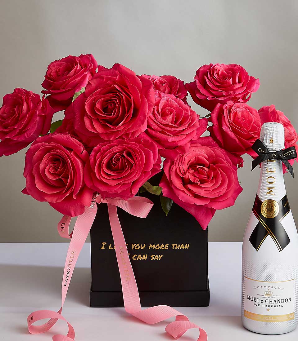 A bouquet of vibrant pink roses in a black box with the words 