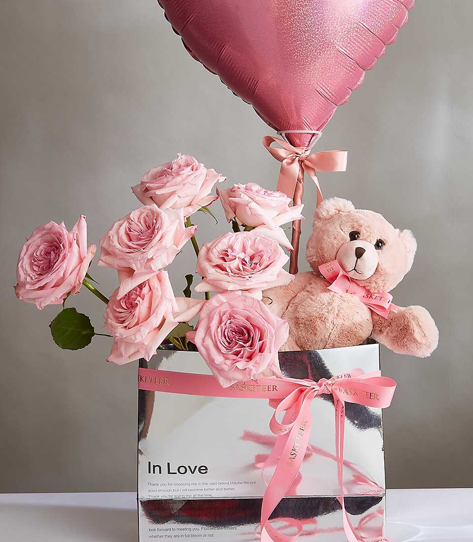 A bouquet of O'Hara pink roses, a soft beige teddy bear, and a heart-shaped pink 