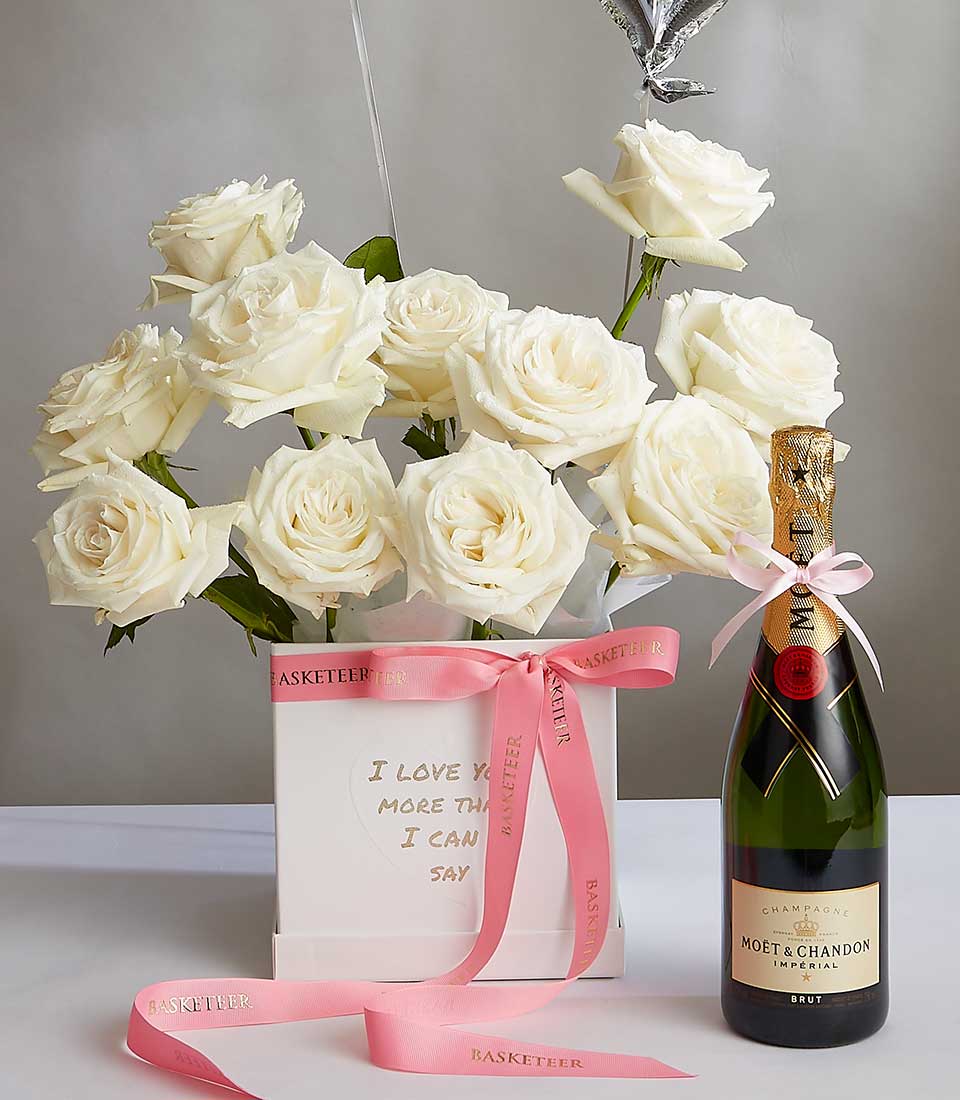 A bouquet of Playa Blanca roses in a white vase, featuring a pink ribbon that says 
