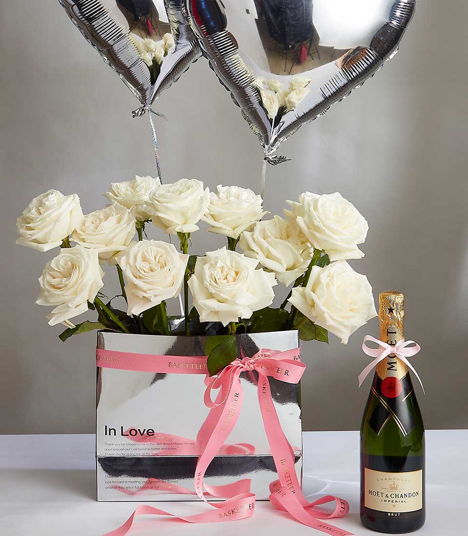 A bouquet of white roses in a reflective box labeled 
