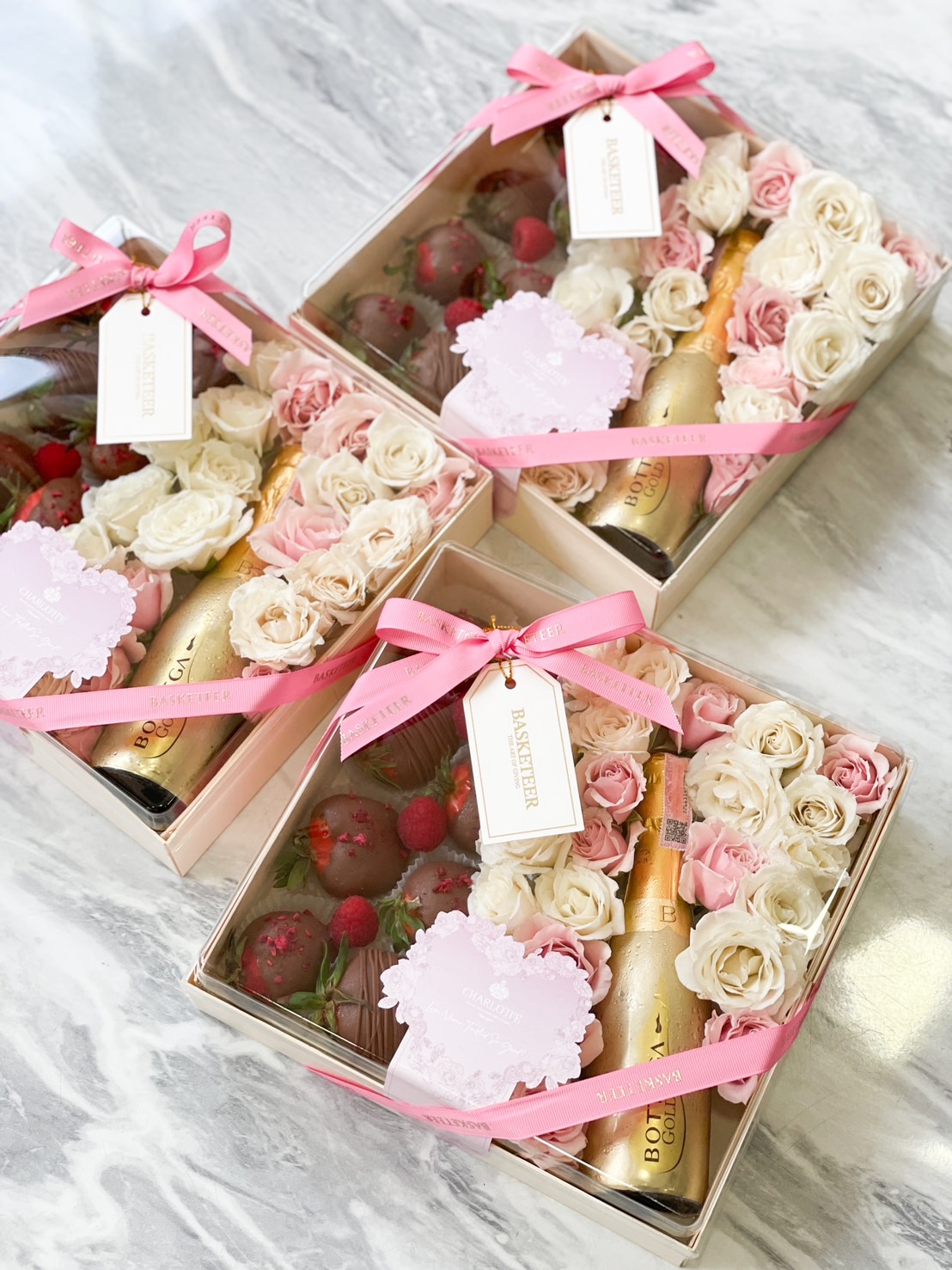 Luxury Valentine’s gift box with chocolate-covered strawberries, champagne, and preserved roses in elegant packaging.