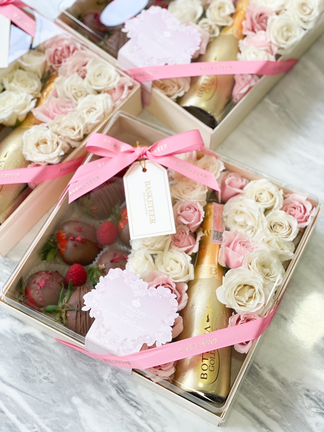 Luxury Valentine’s gift box with chocolate-covered strawberries, champagne, and preserved roses in elegant packaging.