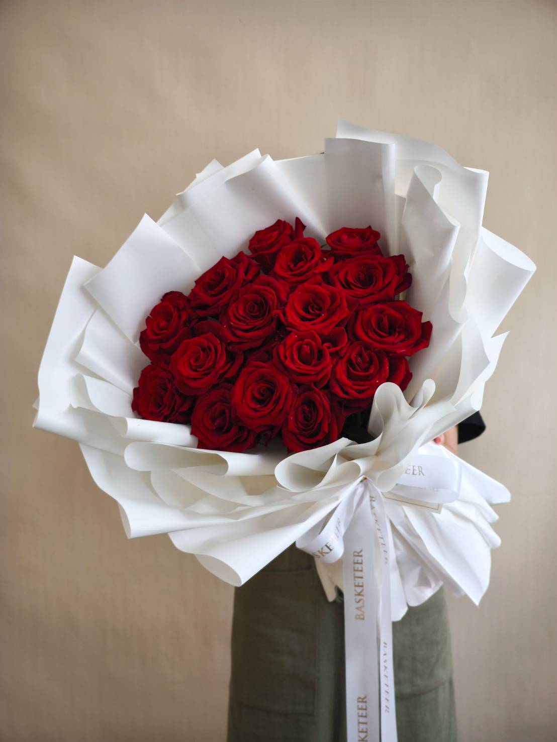 Elegant bouquet of premium red roses wrapped in layered white paper with a satin ribbon. TH: ช่อดอกกุหลาบแดงพรีเมียม ห่อด้วยกระดาษสีขาวซ้อนชั้น ผูกโบว์ริบบิ้นซาติน