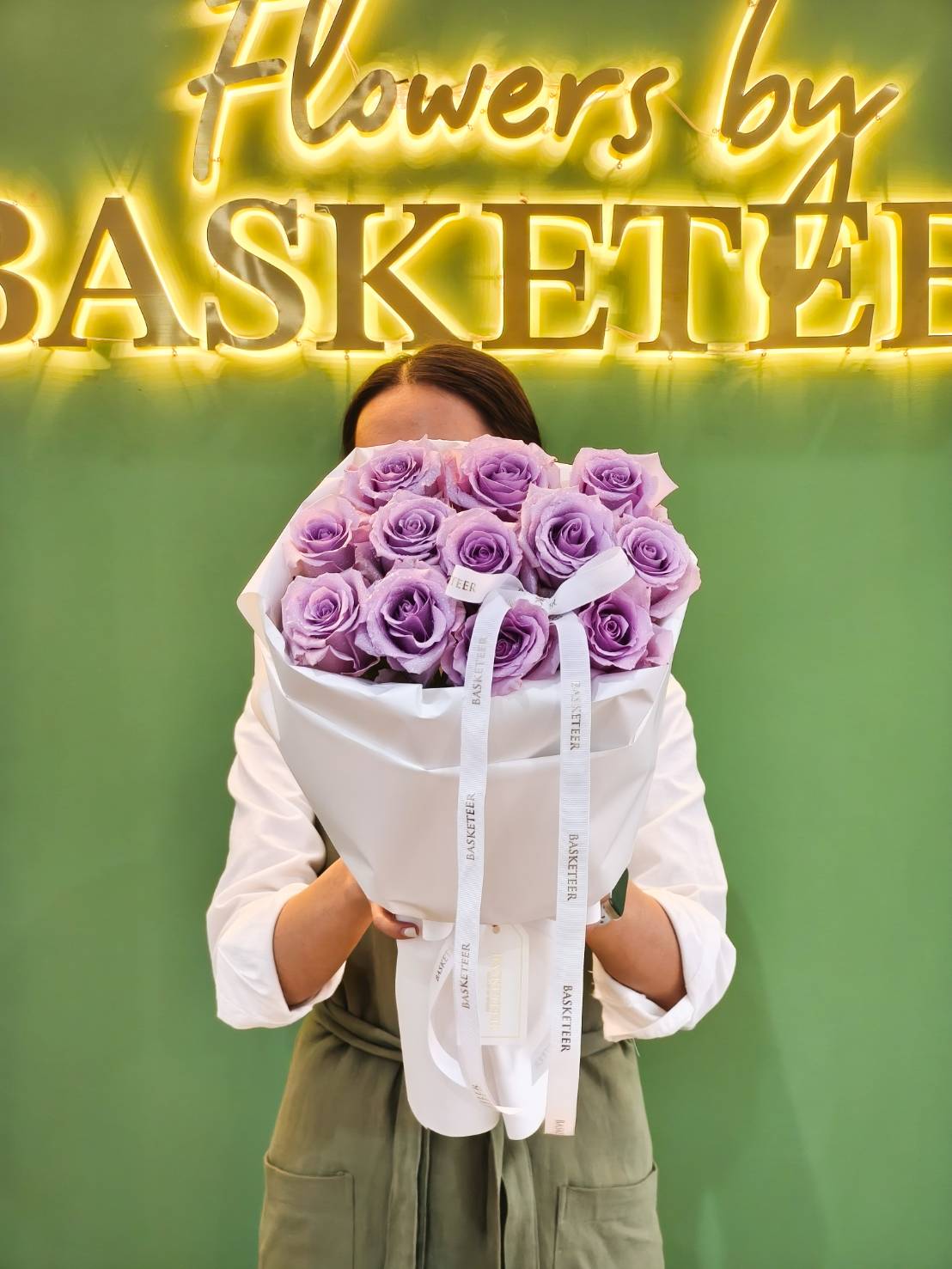 Luxury bouquet of imported purple roses wrapped in white paper with satin ribbon.