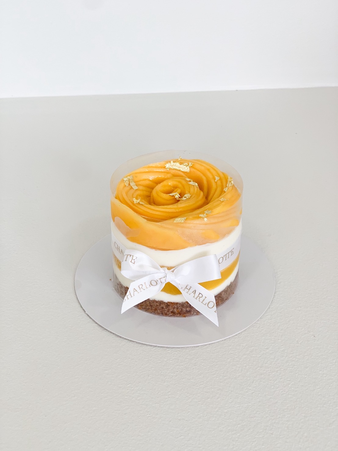 Mini mango cheesecake with golden mango topping and gold leaf decoration.