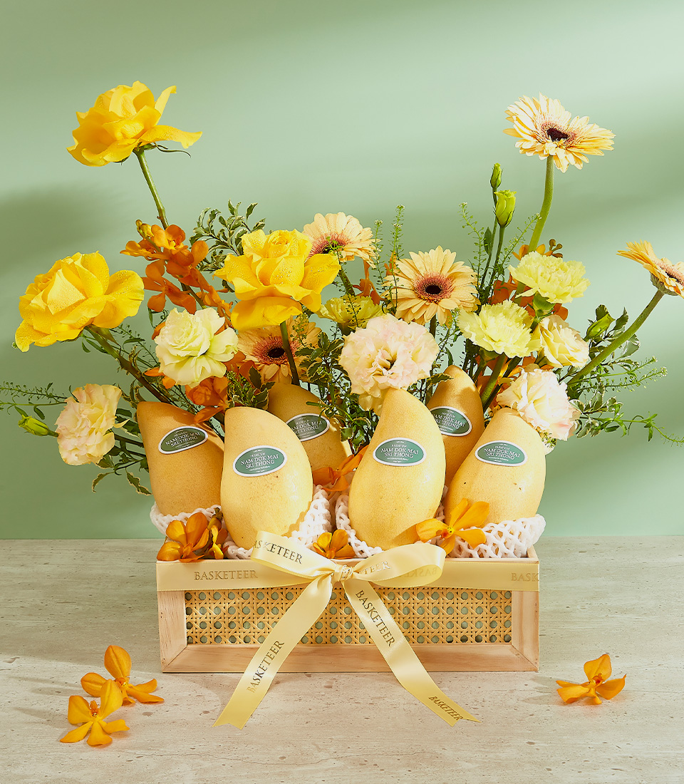 A wooden basket filled with ripe mangoes, labeled as the 