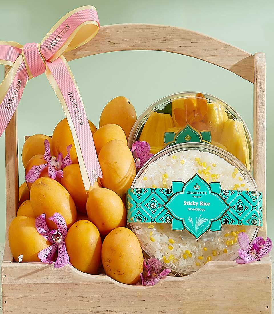 A wooden basket filled with ripe yellow mangoes, decorated with pink ribbon and purple orchids. This Magnificent Mayongchid Gift Basket also includes a container of sticky rice and a container of mango slices, both labeled 