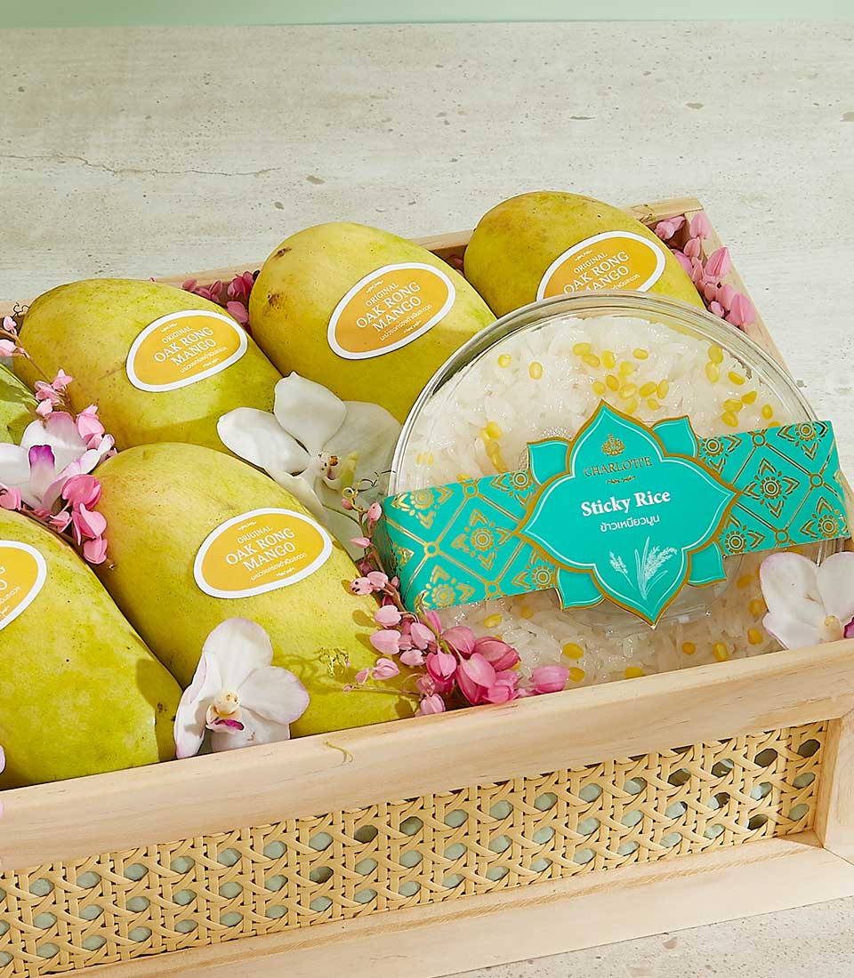 A wooden basket, named the Oak Rong Mango Deluxe Crate, holds yellow mangoes with stickers reading 