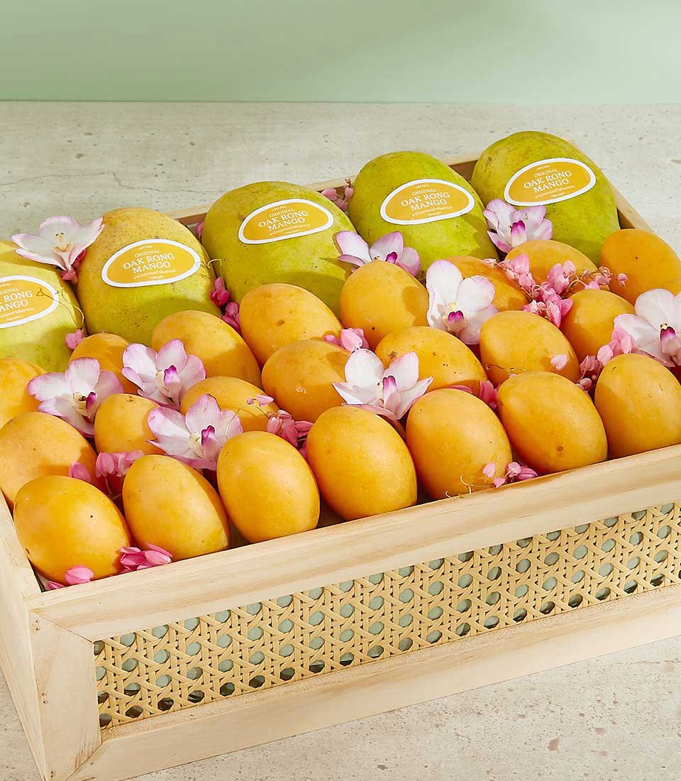 A wooden tray filled with green and yellow mangoes, labeled 