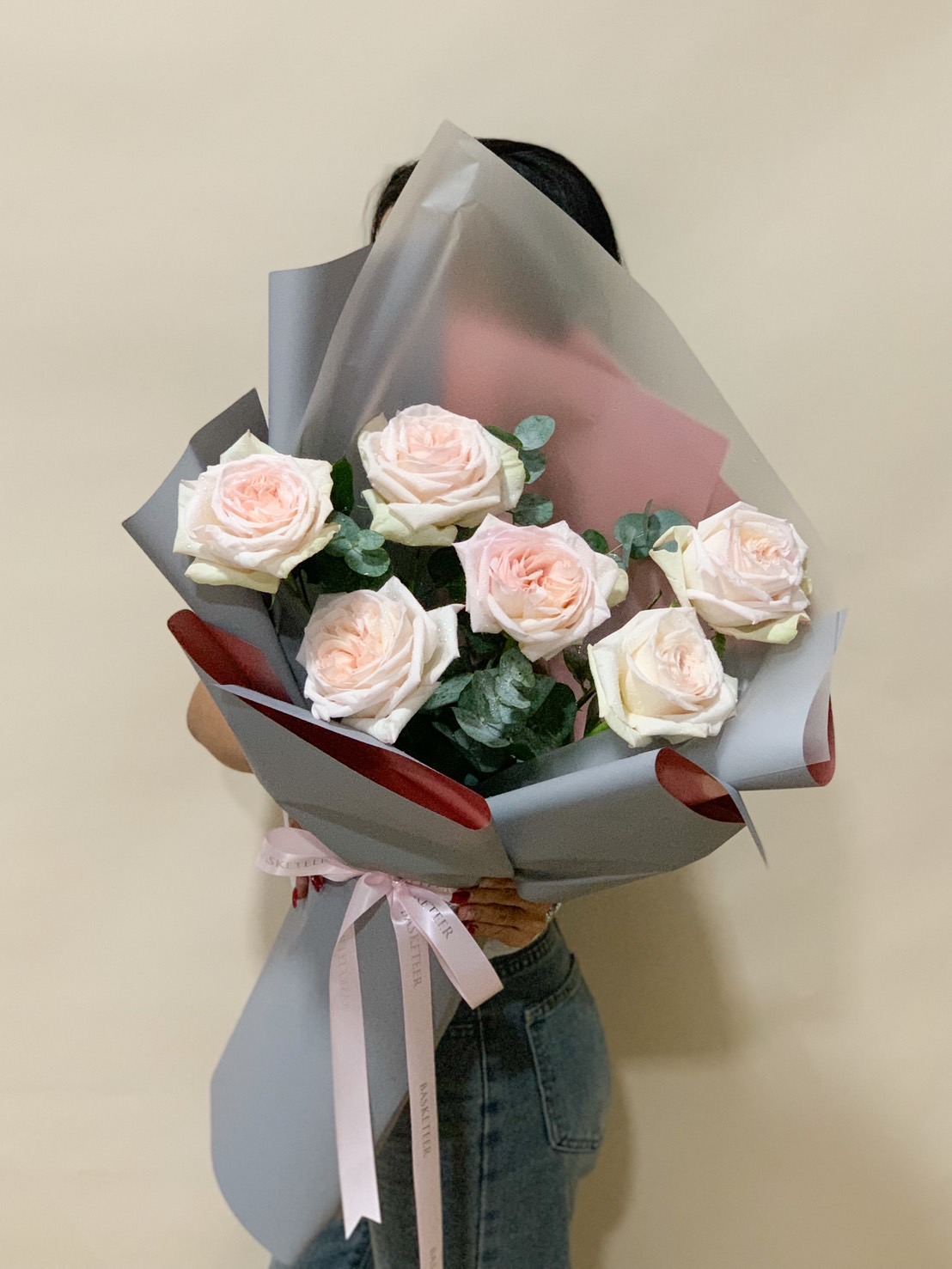 A stunning bouquet of champagne roses with eucalyptus leaves, wrapped in grey and blush-toned paper, tied with a satin ribbon. A timeless and elegant floral gift.