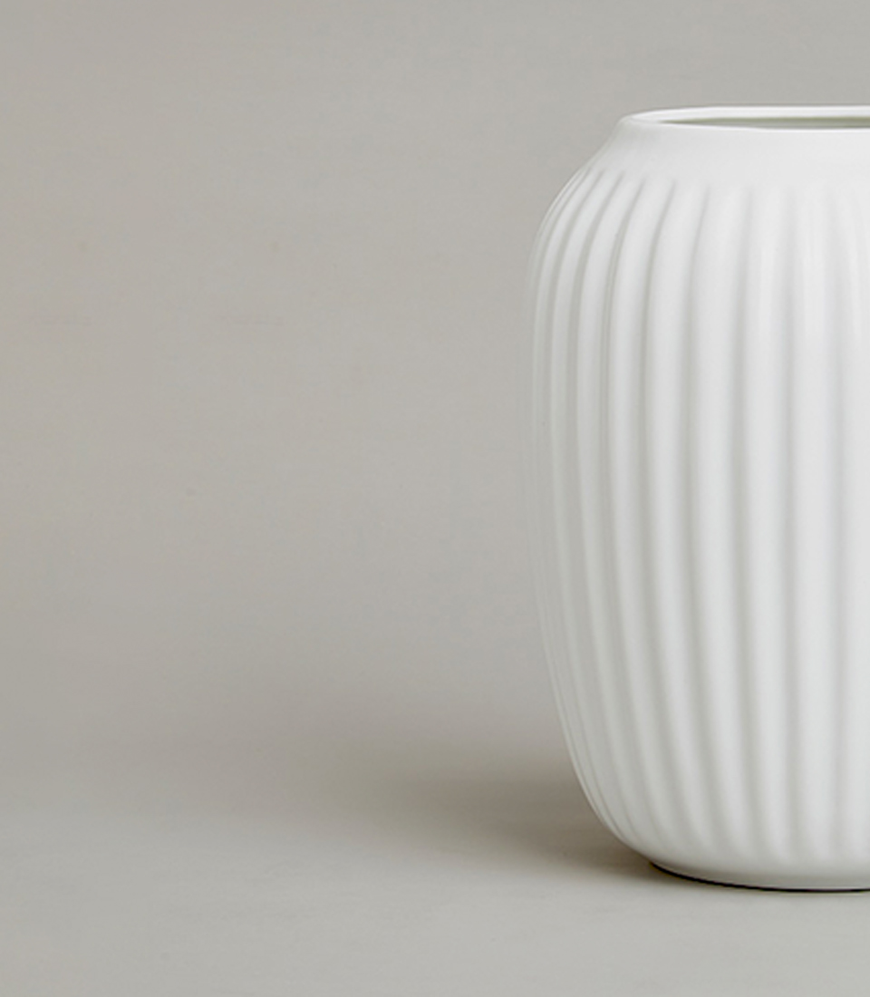 Close-up of modern white ceramic vase with vertical ribbed texture.