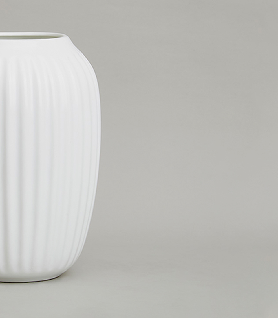 Close-up of modern white ceramic vase with vertical ribbed texture.