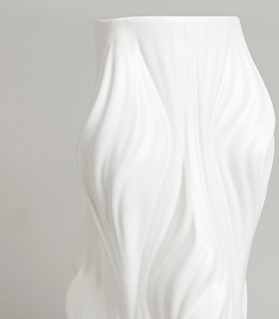 Close-up of white ceramic vase with a flowing wave design.