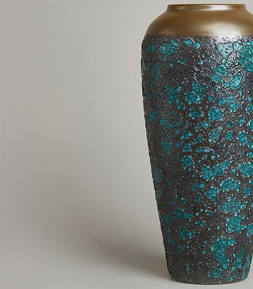 Textured ceramic vase with a turquoise and black speckled design and a gold rim.