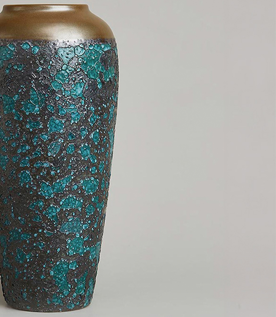 Textured ceramic vase with a turquoise and black speckled design and a gold rim.