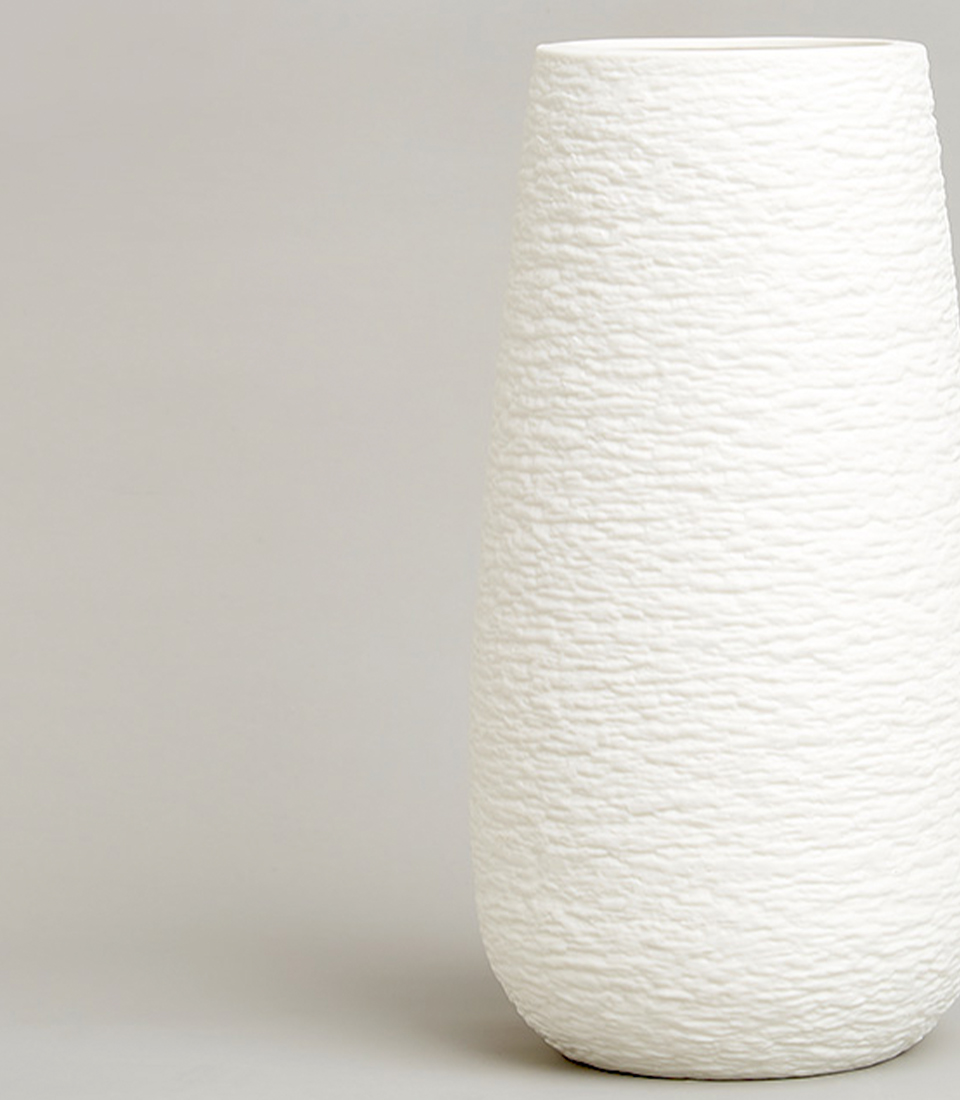 White ceramic vase with textured surface and tapered design.