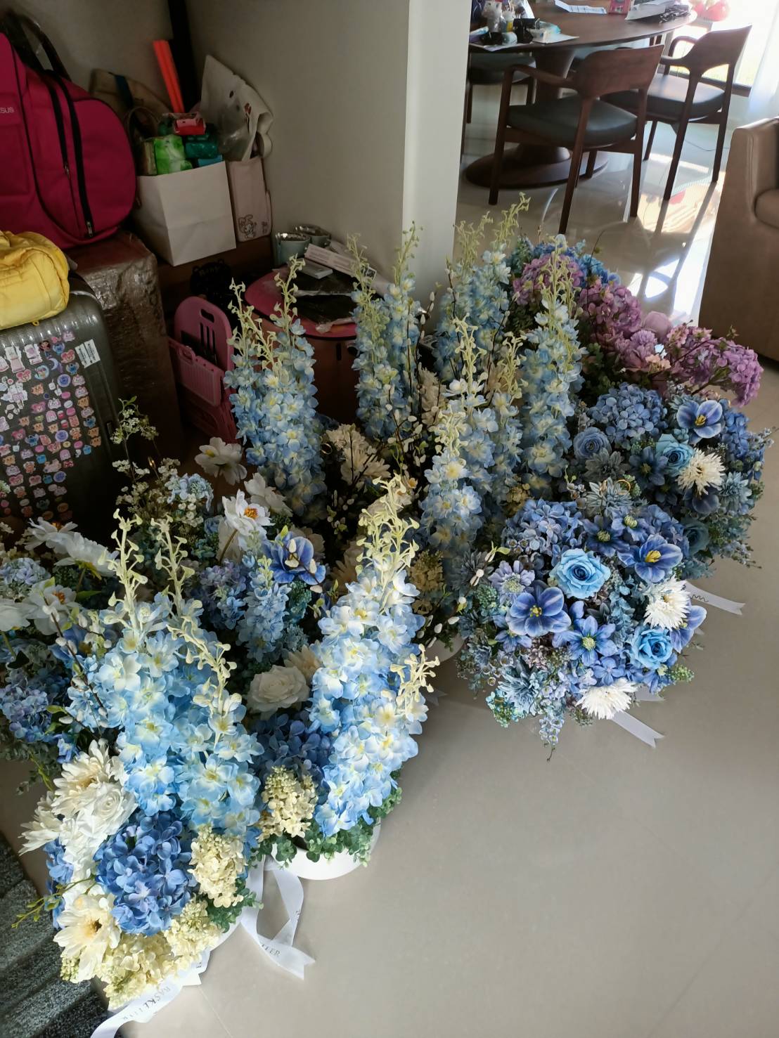 Elegant floral arrangements with blue and white hydrangeas, roses, and delphiniums by Basketeer.