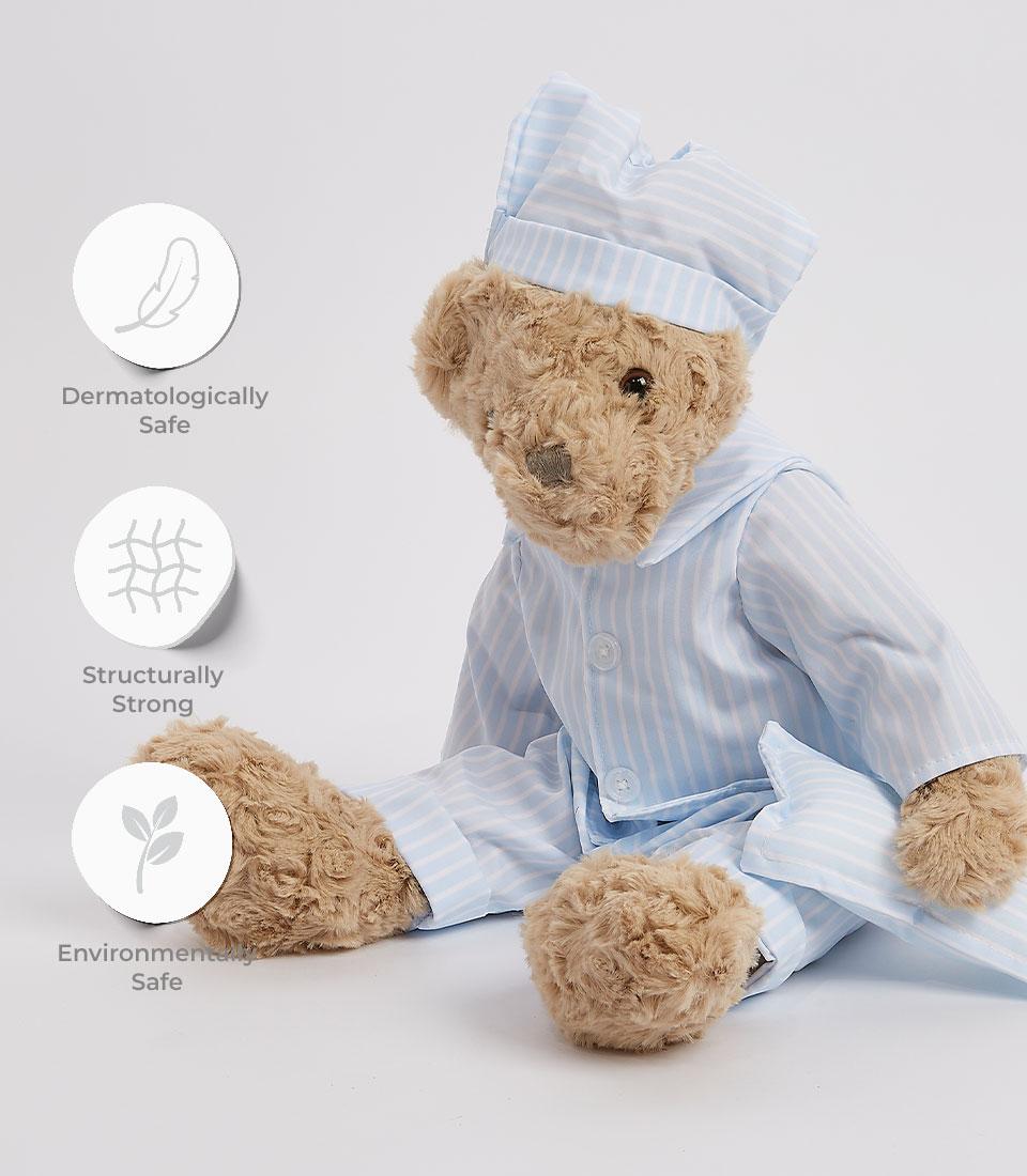A plush teddy bear in striped pajamas and a matching nightcap stands against a plain white background. The soft toy's fur is grey, and it has a slightly serious expression on its face. Next to the soft toy are three circular icons with text: 