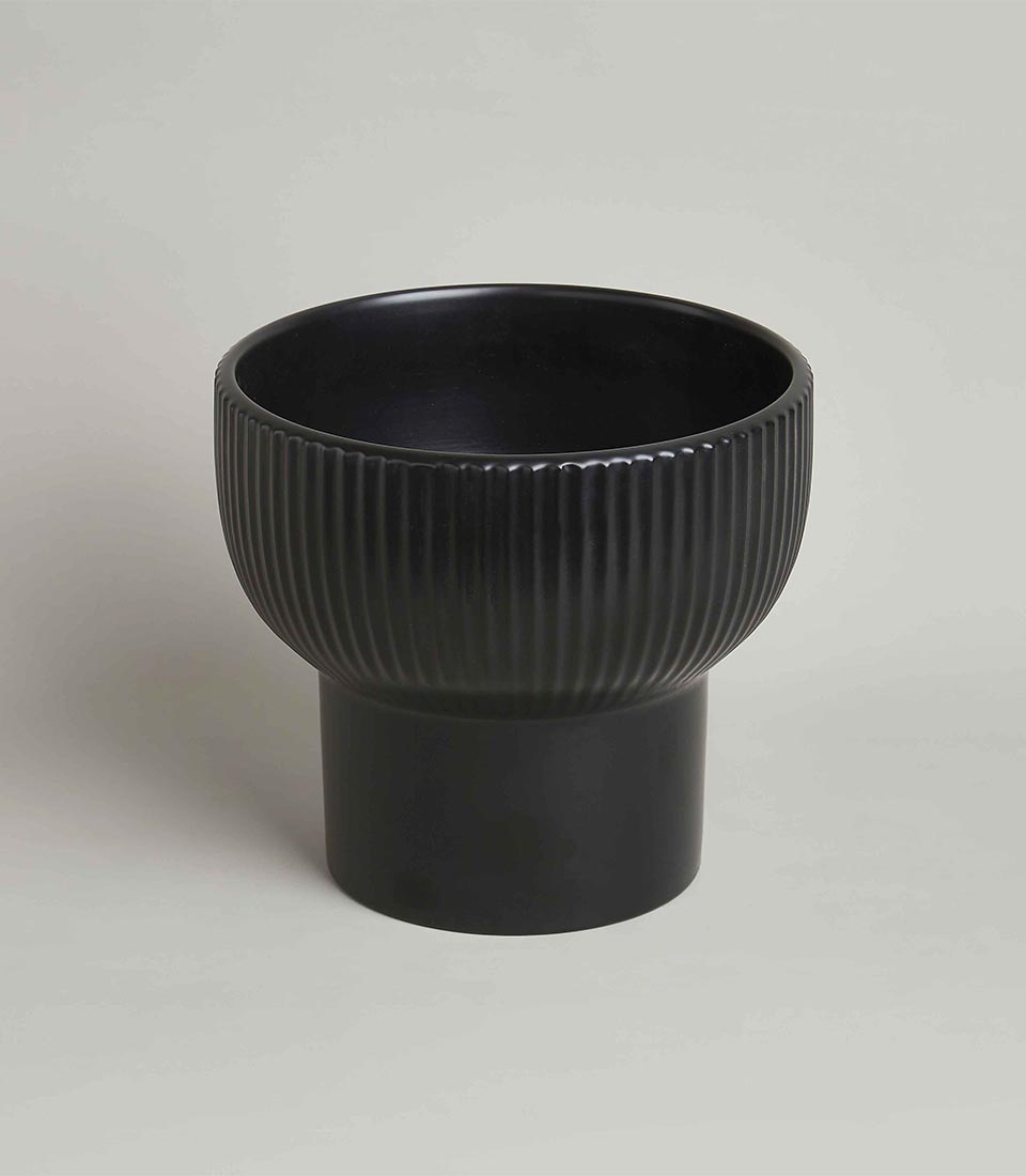 Pair of modern black ceramic planters with ribbed texture and cylindrical bases, in different sizes, on a light grey background