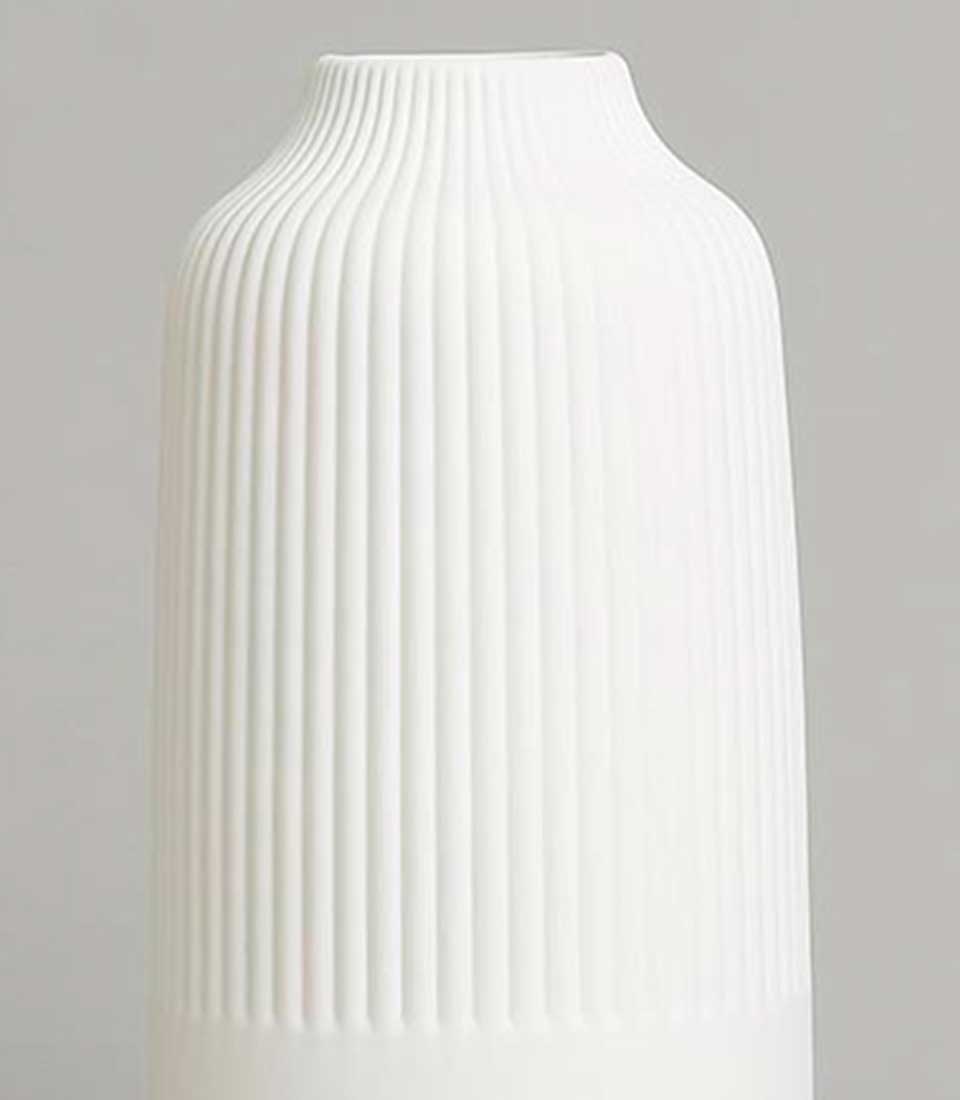 Minimalist tall white ceramic vase with ribbed texture and smooth finish, featuring a sleek cylindrical shape, on a light grey background.