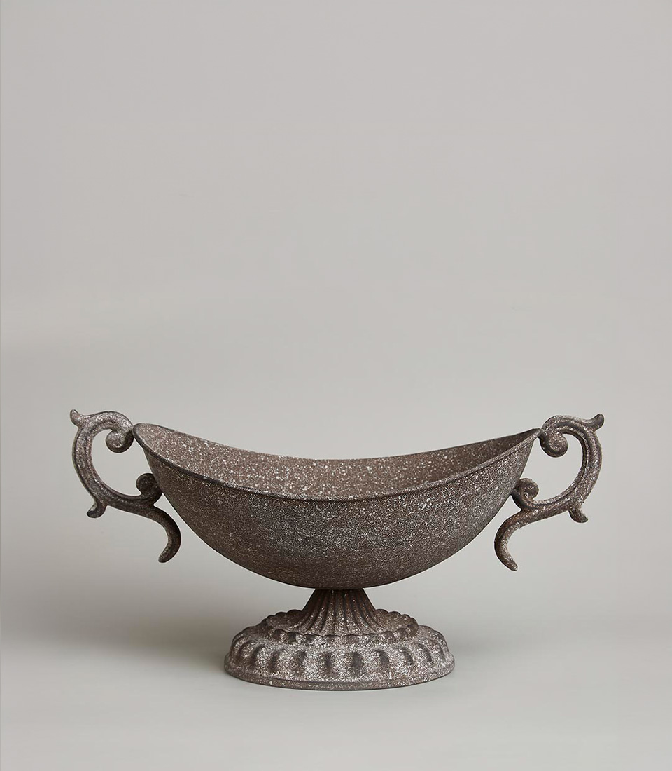 Vintage-style rustic metal urn with ornate handles and a speckled, textured finish, featuring a wide bowl shape on a decorative pedestal base, on a light grey background.