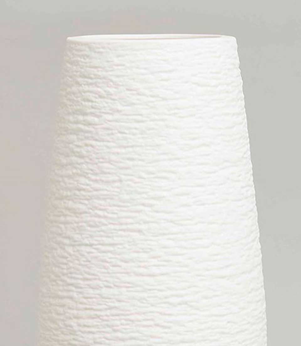 Minimalist tall white ceramic vase with a textured, pebble-like surface and a tapered cylindrical shape, on a light grey background.