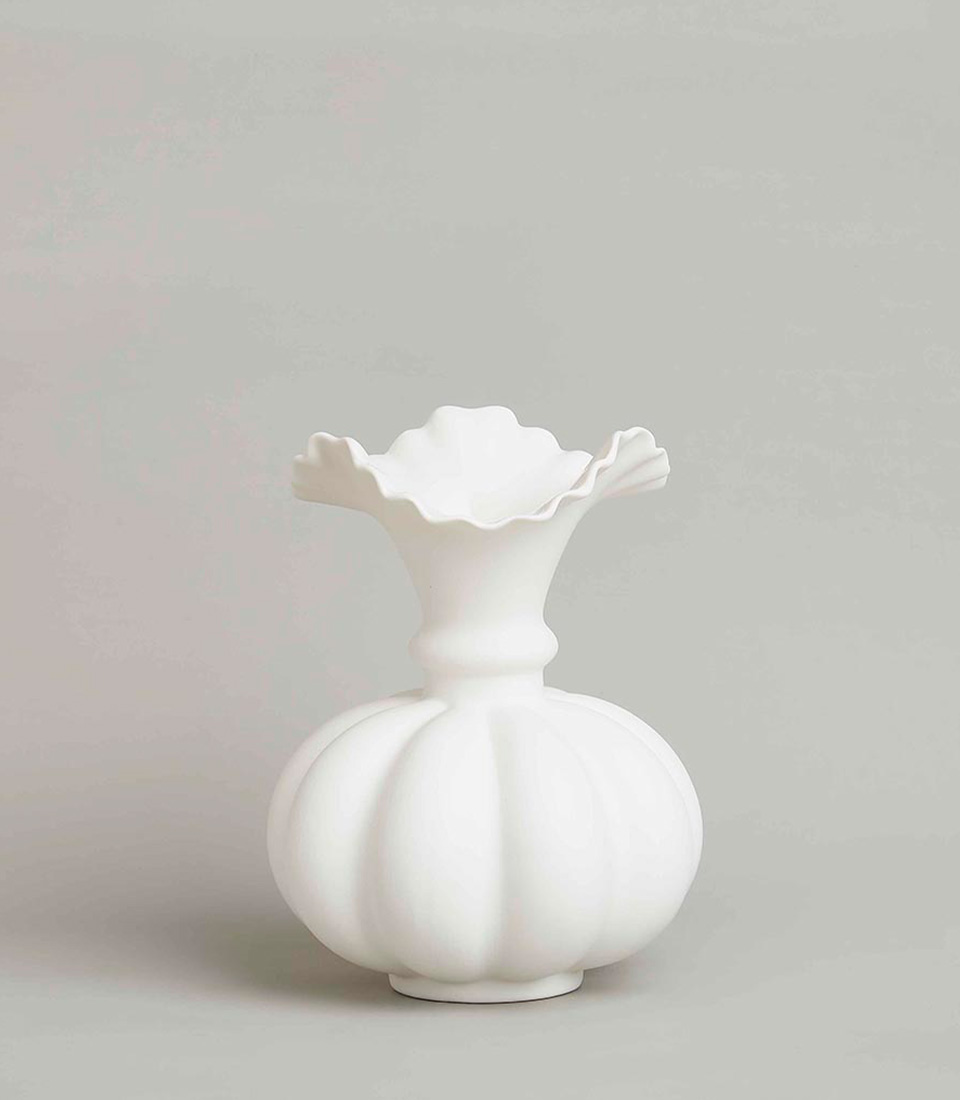 Unique white ceramic vase with a bulbous base and ruffled top rim, featuring a sculptural design and matte finish, on a light grey background.