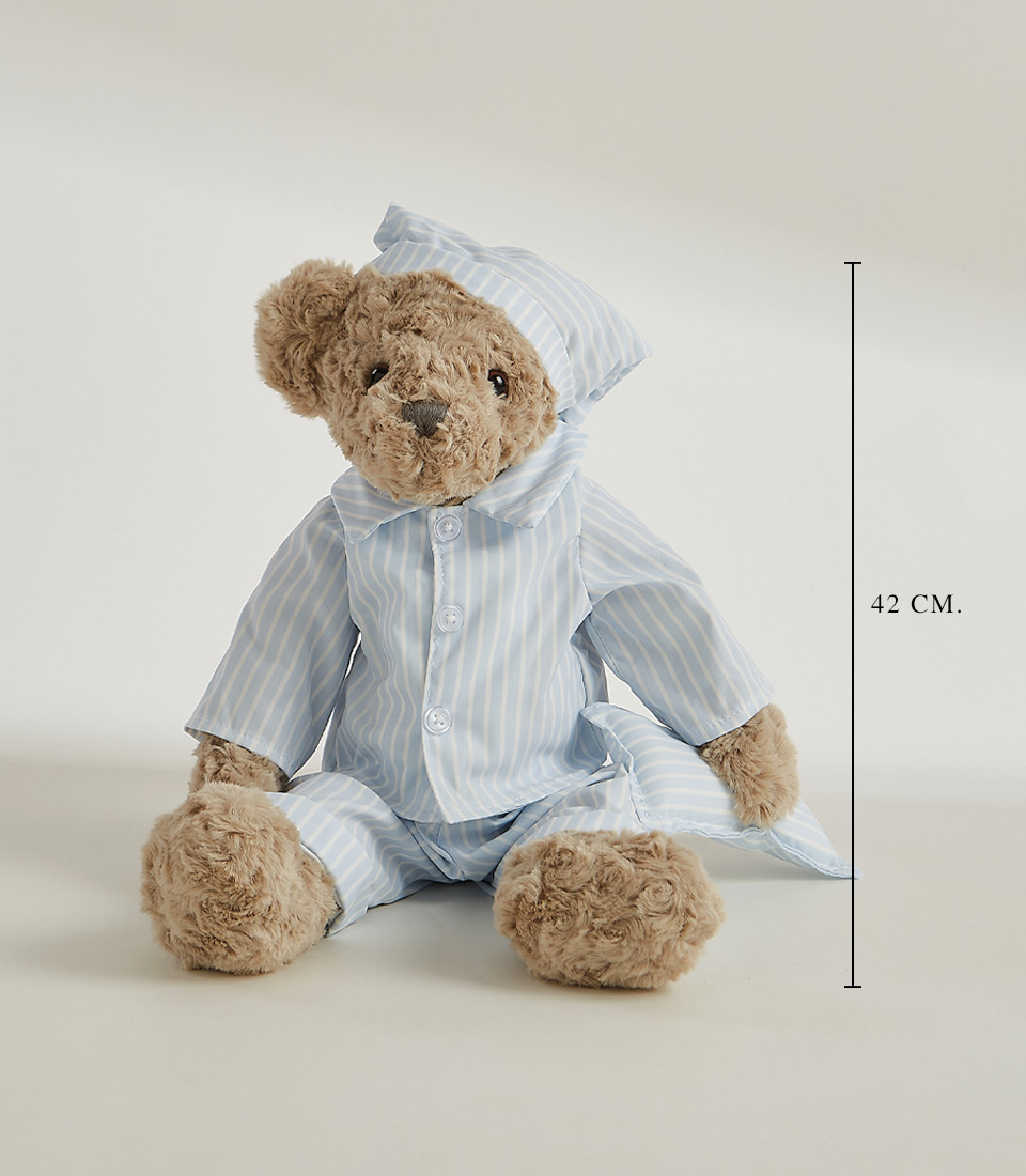 A plush teddy bear in striped pajamas and a matching nightcap stands against a plain white background. The soft toy's fur is grey, and it has a slightly serious expression on its face.