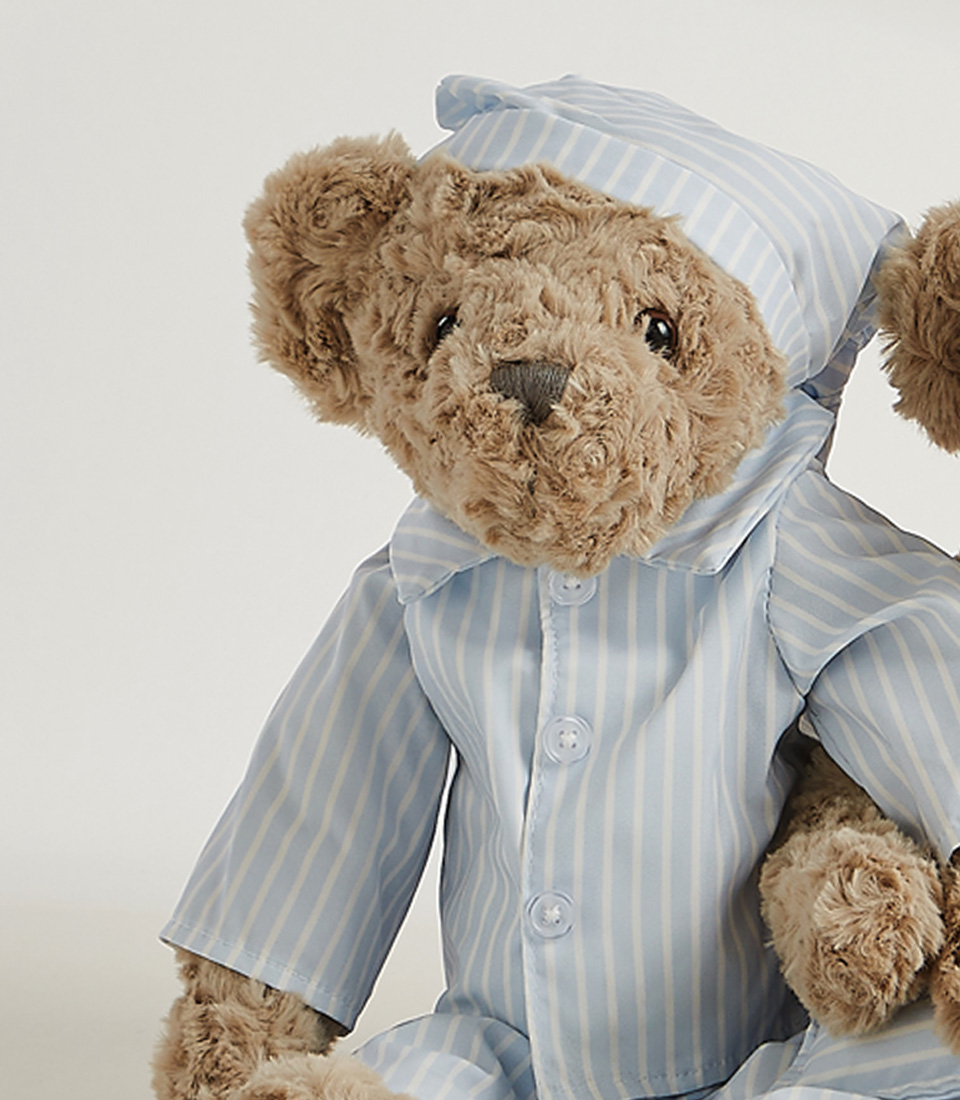 The Sleepytime Teddy Bear Duo Soft Toys feature two plush teddy bears dressed in striped pajamas and nightcaps. The larger bear wears a pink nightgown with a matching pink cap, while the smaller bear is snug in a blue pajama set with a matching blue nightcap.
