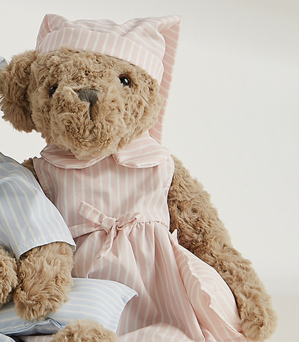 The Sleepytime Teddy Bear Duo Soft Toys feature two plush teddy bears dressed in striped pajamas and nightcaps. The larger bear wears a pink nightgown with a matching pink cap, while the smaller bear is snug in a blue pajama set with a matching blue nightcap.