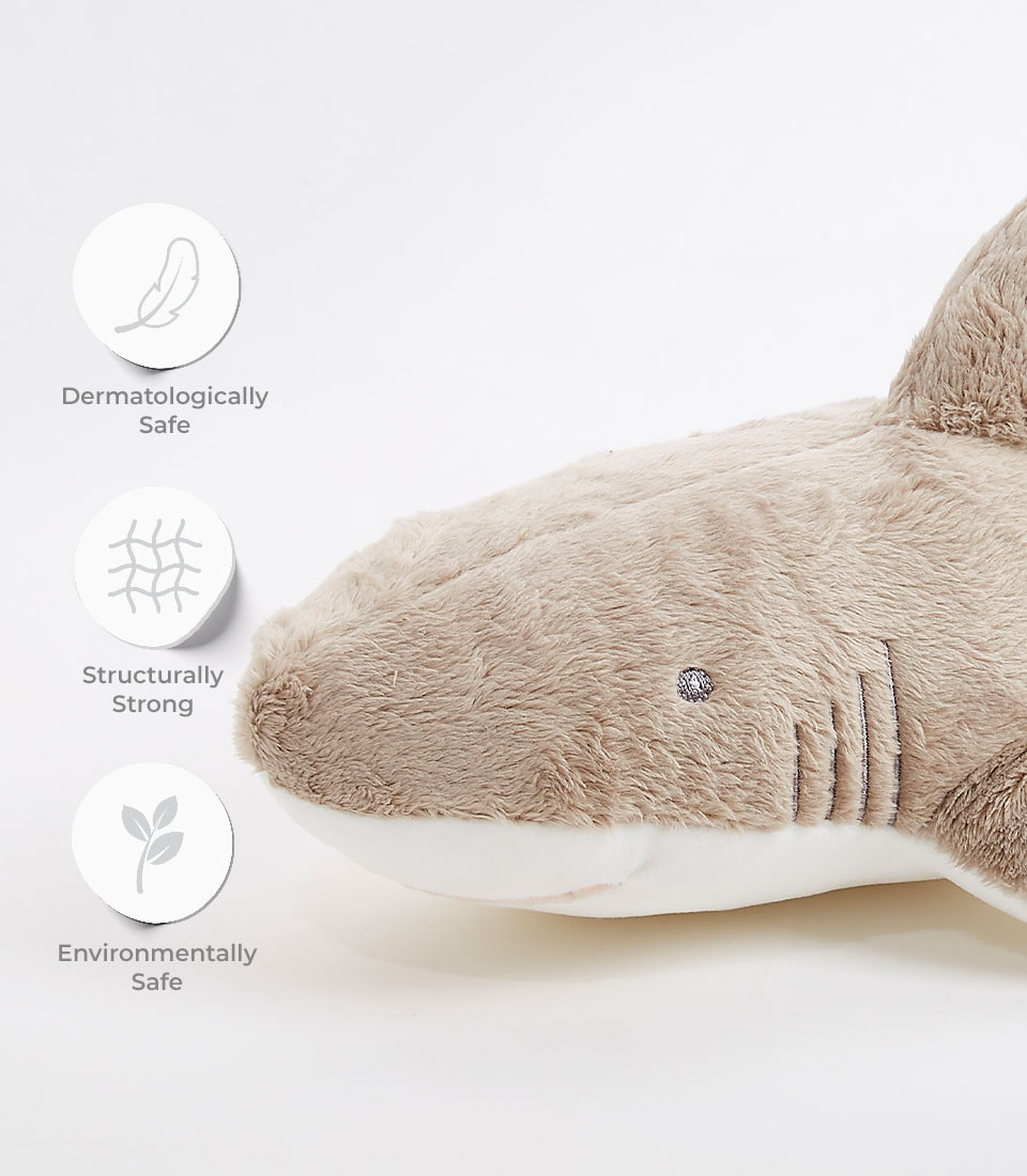 Close-up of a Plush Shark Soft Toy with text and icons highlighting its benefits. Icons depict a feather for 