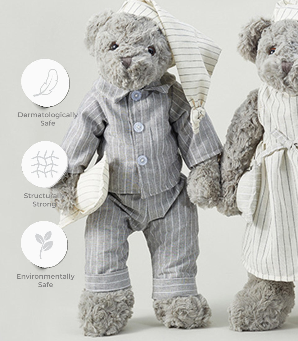 A Sleepytime Teddy Bear Duo, each donning blue and white striped pajamas with matching nightcaps, stands side by side. Icons and text nearby indicate that the soft toys are dermatologically safe, structurally strong, and environmentally friendly.