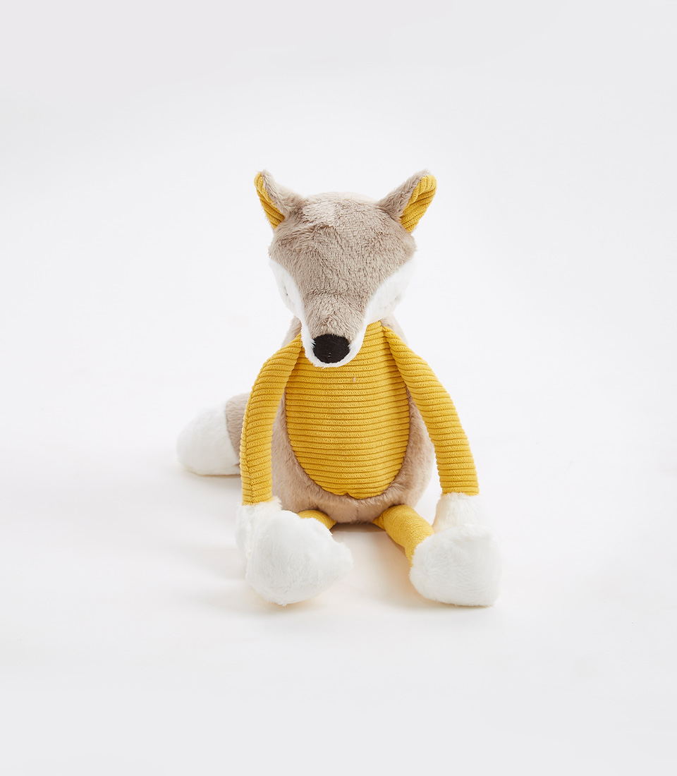 A plush yellow and gray fox sits against a white background. The fox has a beige and white body, yellow ribbed fabric on its front, and white paws. Its head is slightly tilted forward, showcasing its soft toys charm with a cozy, plush appearance.
