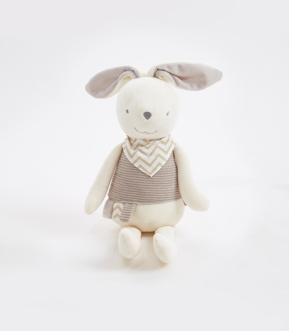 A gray bunny plush toy with chevron bib is sitting upright. It has long, soft ears that are gray on the inside and white on the outside. The bunny is wearing a gray and white striped outfit with a matching scarf. The background is plain white.