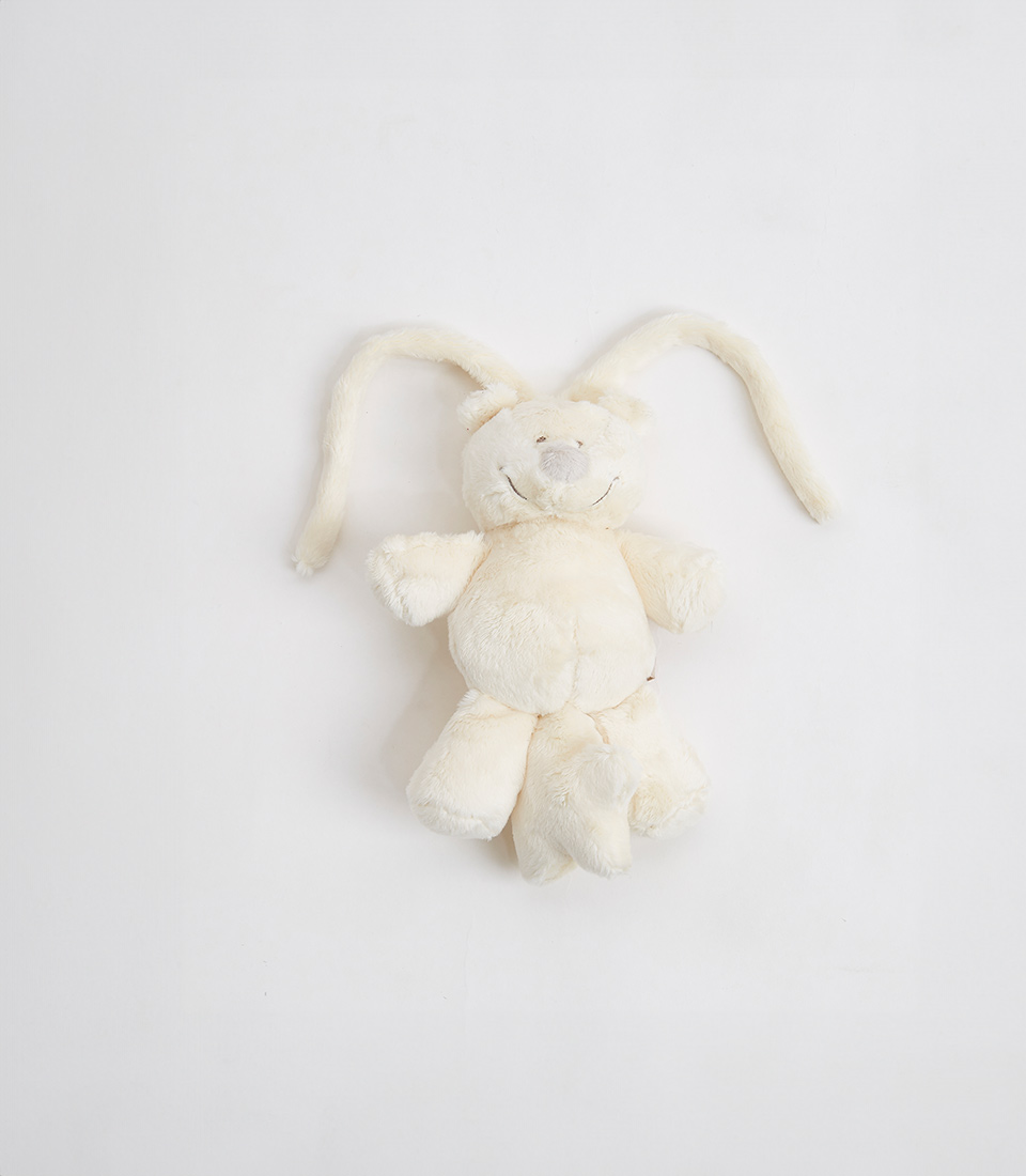 A plush toy bunny with long ears and cream-colored fur is pictured against a plain white background, reminiscent of a White Teddy Bear with its soft and cuddly appearance. Positioned vertically with its ears pointing upward, the simple and cute design makes it an ideal addition to any collection of soft toys.