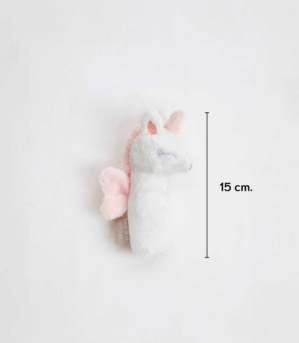 A soft unicorn plush toy bolster with pink accents lies on a white background. The toy, standing 15 cm tall, features a pink mane, tail, and inner ears along with a pink fabric tag attached.