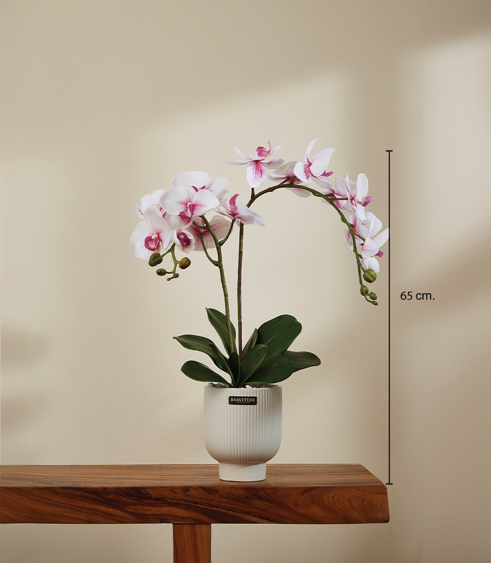 Lifelike white and pink Phalaenopsis orchid flowers with realistic green stems and leaves arranged in a decorative pot. This alt text captures the key features of the orchid and the overall look of the arrangement.