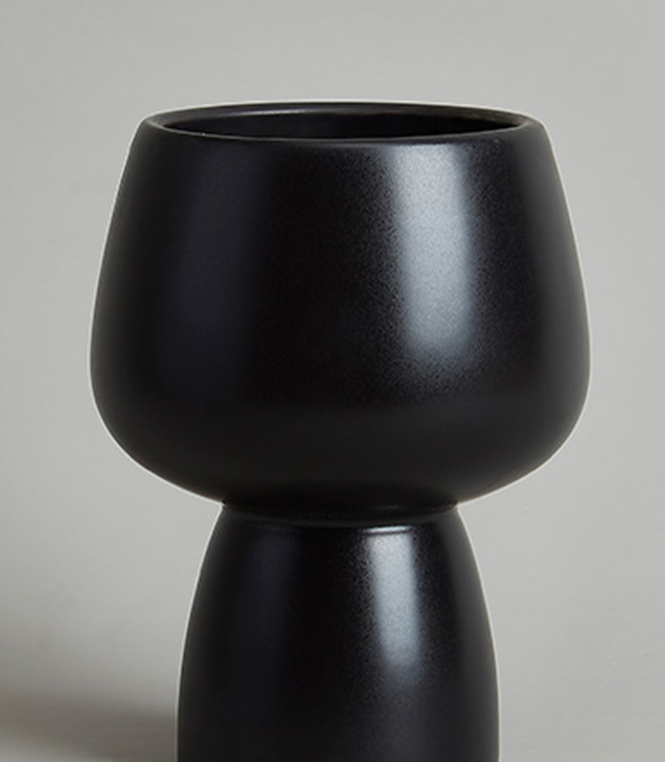Close-up of a modern black ceramic vase with a rounded top and tapered base.