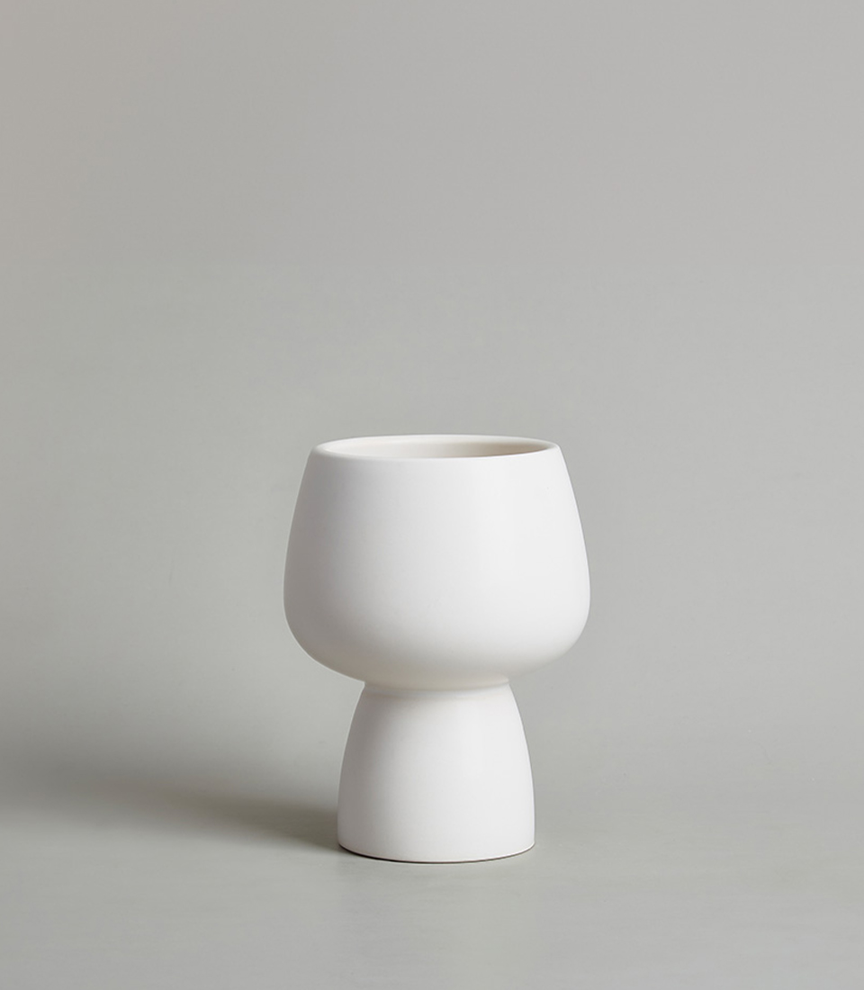 Modern white ceramic vase with a minimalist design, featuring a rounded bowl-shaped top and a narrow base with a light gray background.