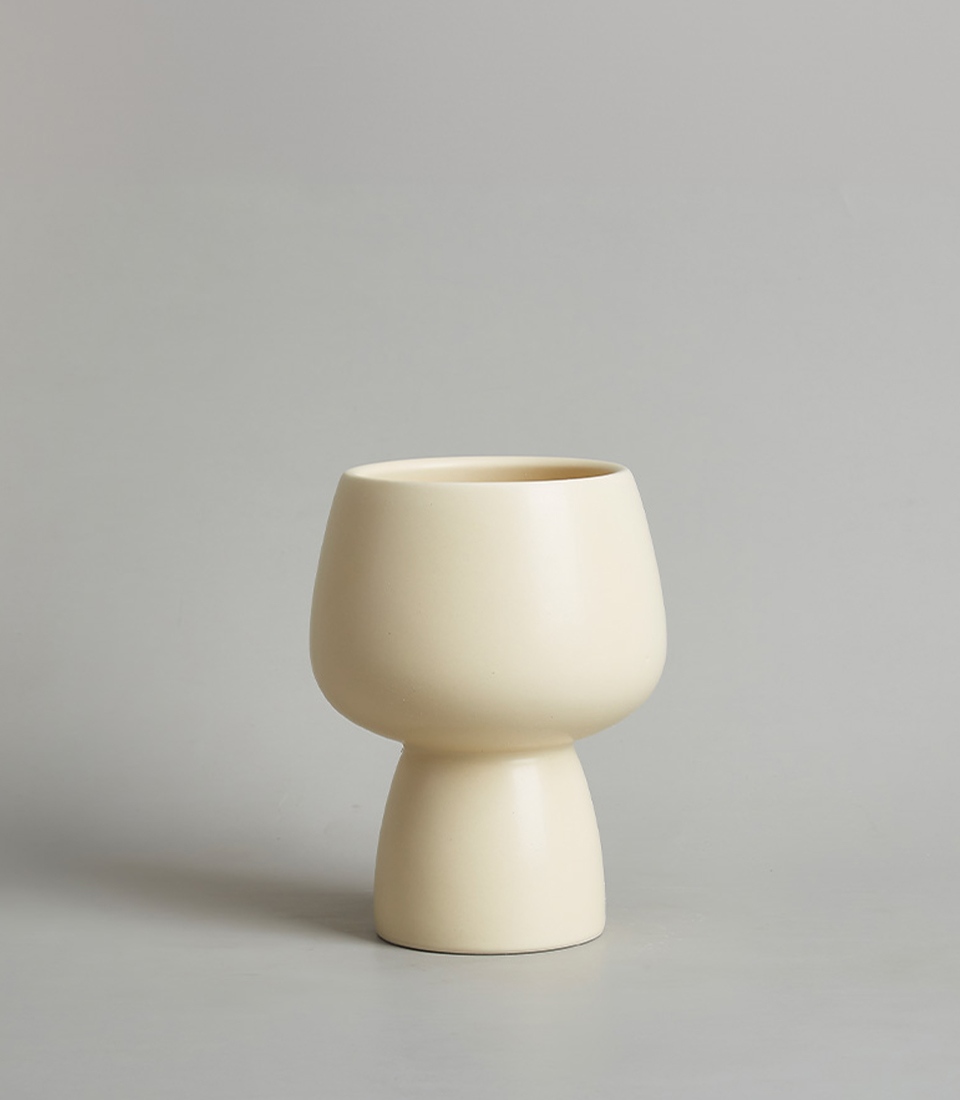 Modern beige ceramic vase with a minimalist design, featuring a rounded bowl-shaped top and a narrow base with a light gray background.