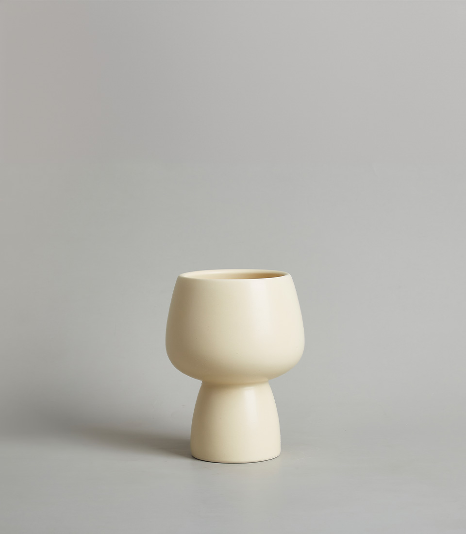 Modern cream-colored ceramic vase with a minimalist design, featuring a rounded bowl-shaped top and a narrow base, against a neutral background.