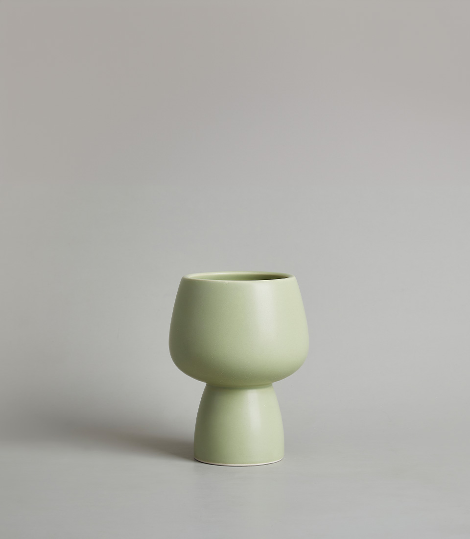 Modern light green ceramic vase with a minimalist design, featuring a rounded bowl-shaped top and a narrow base, against a neutral background.