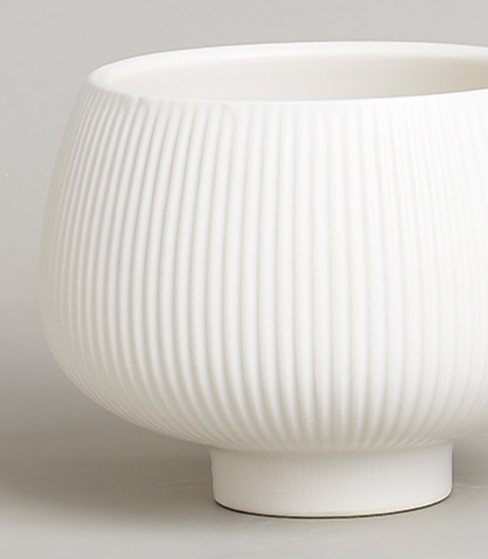 Close-up view of a white ribbed ceramic bowl-shaped vase.