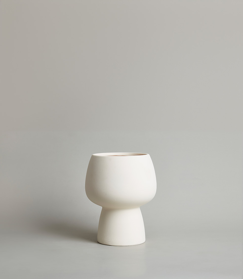 Minimalist white ceramic vase with a modern, sculptural design against a neutral background.