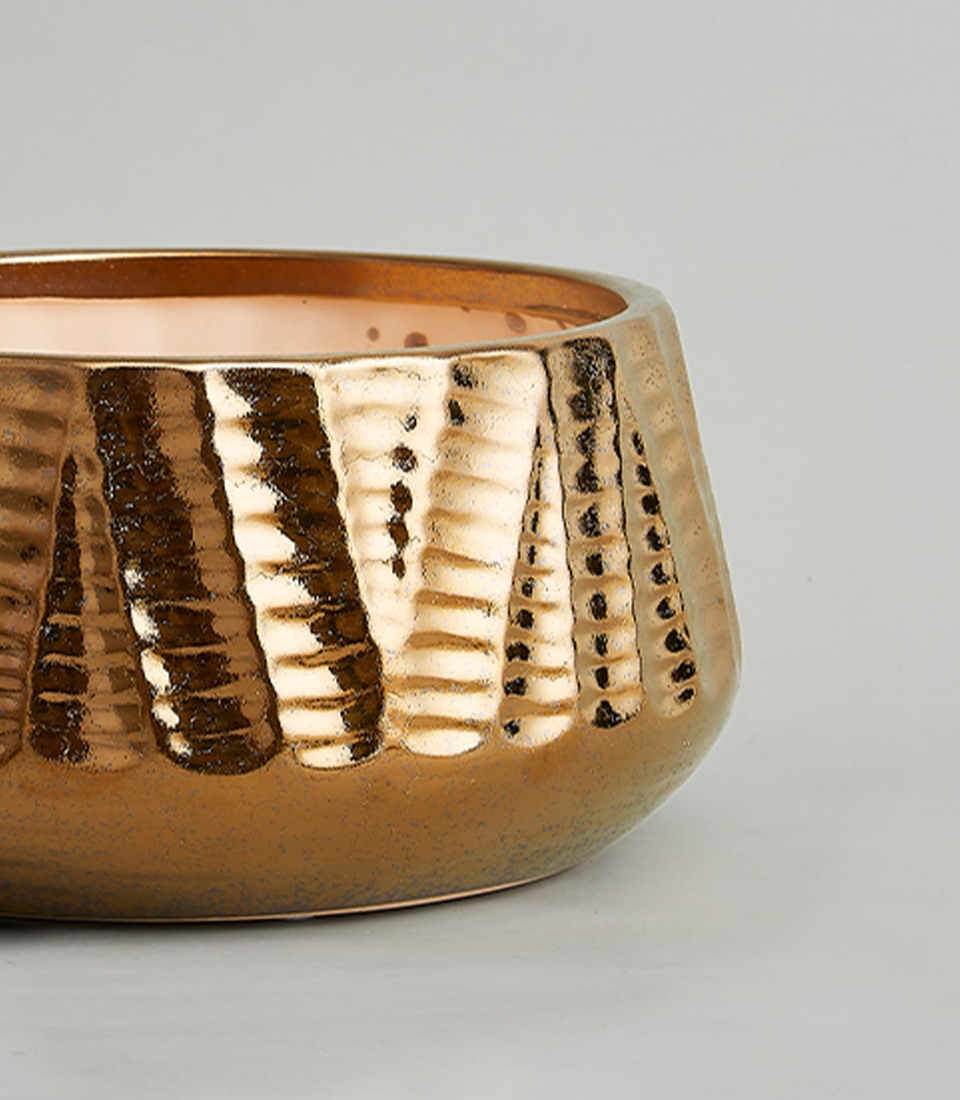 Close-up of a metallic bronze textured ceramic vase with a wide, round shape.