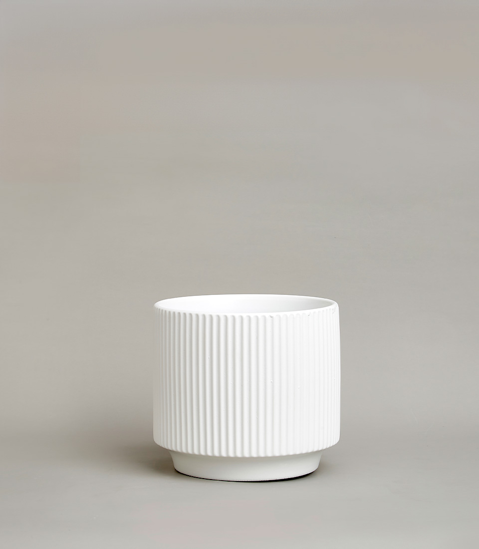 White ribbed ceramic vase with a modern design against a neutral background.