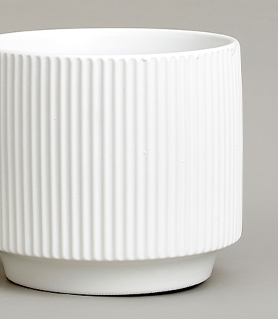 Close-up of a White ribbed ceramic vase with a modern design.
