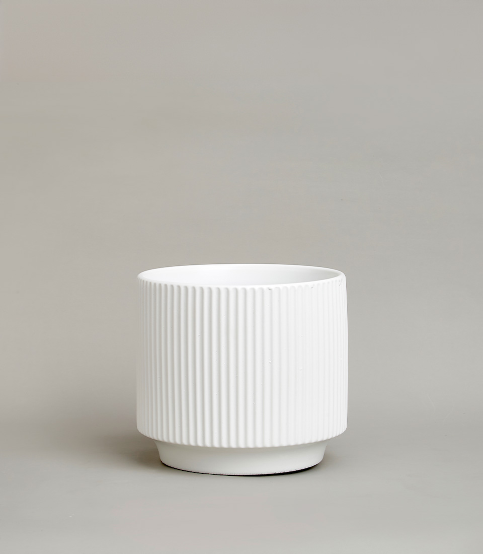 White ribbed ceramic vase with a modern design against a neutral background.